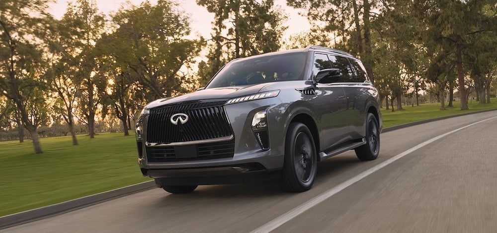 A gray 2026 Infiniti QX80 SUV driving down a road