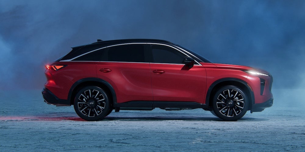 A side view of a red 2027 INFINITI QX65 SUV at night