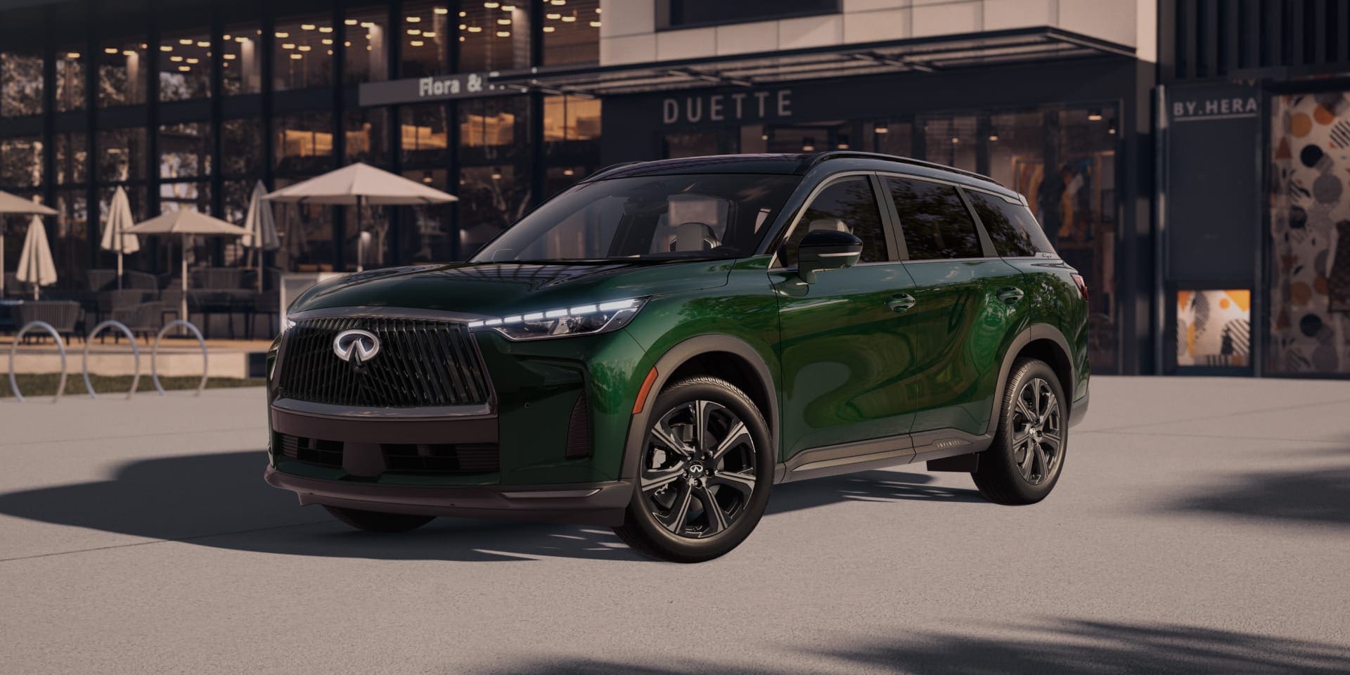 A green INFINITI QX60 parked outside of a building