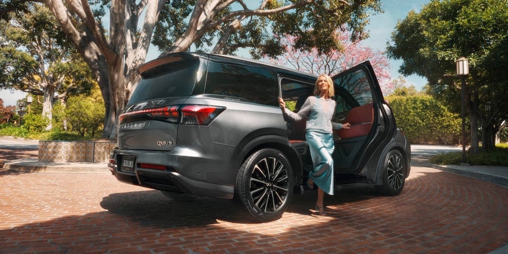 A woman stepping out of a gray 2026 Infiniti QX80 SUV